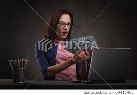 Successful businesswoman at the table on a dark background with laptop and money. 60413462