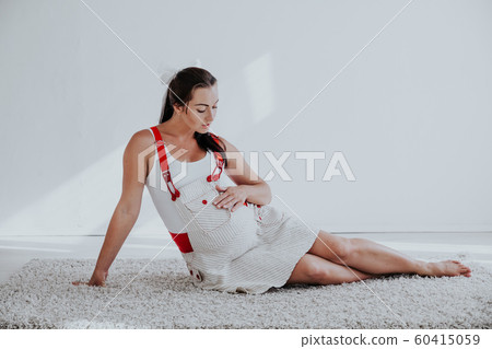 a pregnant woman sitting on the floor talking with a baby in the belly 60415059