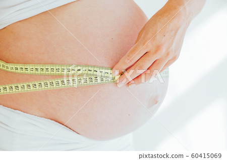 the stomach of a pregnant woman and a measuring tape the stomach of a pregnant woman and a measuring tape 60415069