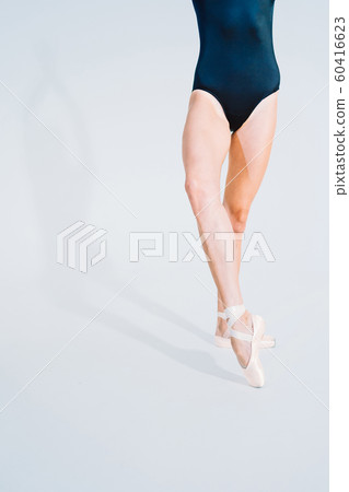 Close up of ballet dancer's legs in pointe. Woman practices exercises on white studio background. Ballerina's feet in shoes. Girl shows classic ballet pas. Close up of ballet dancer's legs in pointe. Woman practices exercises on white studio background. Ballerina's feet in shoes. Girl shows classic ballet pas. 60416623