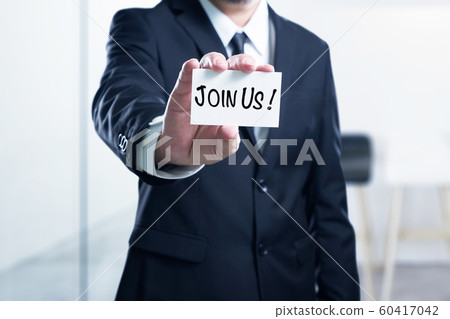 Man's hand showing "Join Us" business card - closeup shot on blur office background , Job recruitment advertisement concept . 60417042
