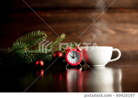 Red alarm clock and cup of hot drink on wooden table 60420197