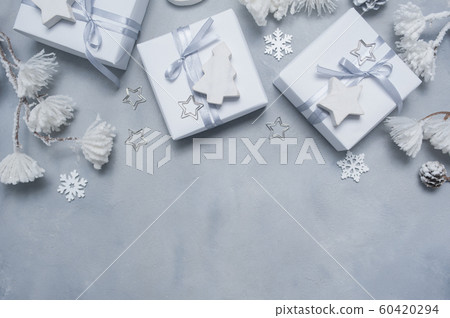 Border Design a Christmas greeting card with Xmas gift box, cones, snowflakes with place for your text. Decorations on a white concrete background 60420294