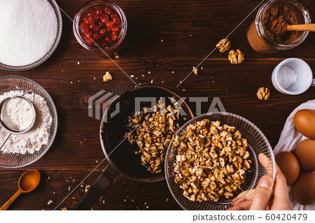 Woman's hand adding chopped walnuts Woman's hand adding chopped walnuts 60420479