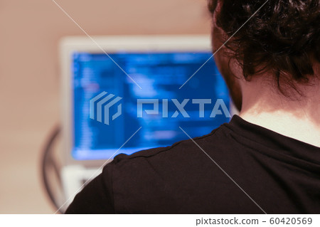 Young programmer writes code in a programming language on a laptop. The view from the back. Blurred background and copy space. Application Development Young programmer writes code in a programming language on a laptop. The view from the back. Blurred background and copy space. Application Development 60420569