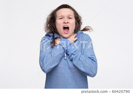 Female teenager in blue clothes feeling storng pain in throat choking herself ith hands. Female teenager in blue clothes feeling storng pain in throat choking herself ith hands. 60420790