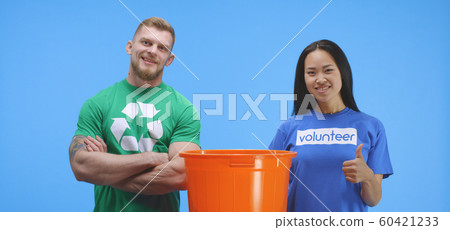 Eco-conscious man and woman putting bottle into bucket Eco-conscious man and woman putting bottle into bucket 60421233