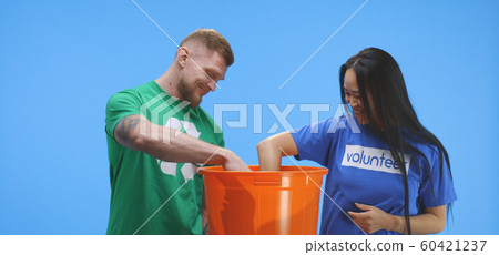 Eco-conscious man and woman putting bottle into bucket 60421237