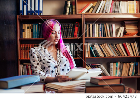 girl reading a book in the library is preparing for exams 60423478