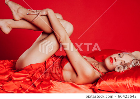 blonde woman in red underwear lies on the bed 60423642