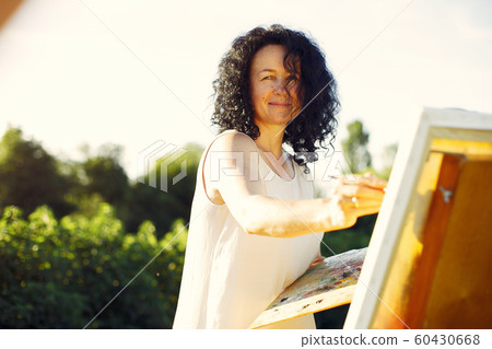 Beautiful adult woman drawing in a summer field Beautiful adult woman drawing in a summer field 60430668