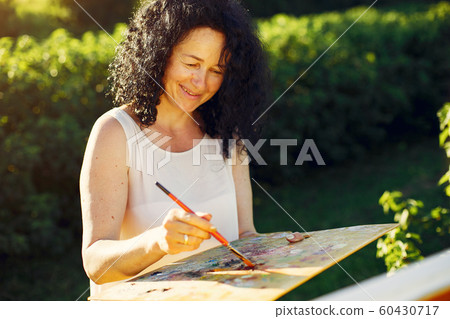 Beautiful adult woman drawing in a summer field 60430717