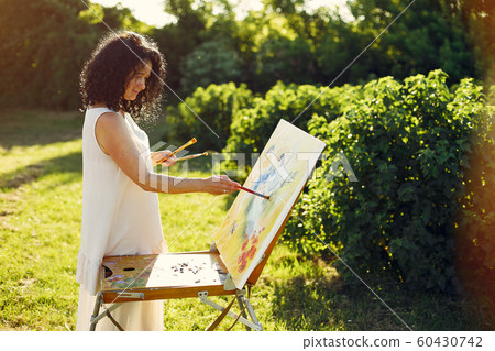 Beautiful adult woman drawing in a summer field 60430742