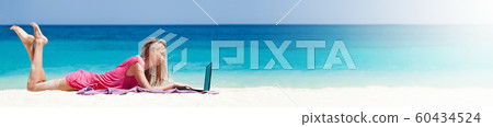 Blond girl with a laptop on tropical beach 60434524