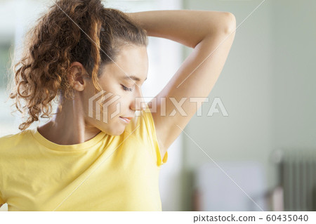 Young woman smelling her armpits Young woman smelling her armpits 60435040
