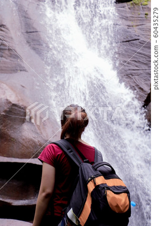 women seeing waterfall. Tourist show hands up and enjoying waterfall. A man enjoying free happiness in beautiful Thailand landscape. women seeing waterfall. Tourist show hands up and enjoying waterfall. A man enjoying free happiness in beautiful Thailand landscape. 60435279