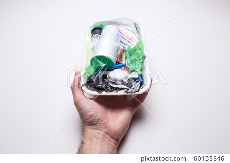 Male hand holds a tray with plastic waste on a white isolated background. The problem of ecology and environmental pollution. Male hand holds a tray with plastic waste on a white isolated background. The problem of ecology and environmental pollution. 60435846