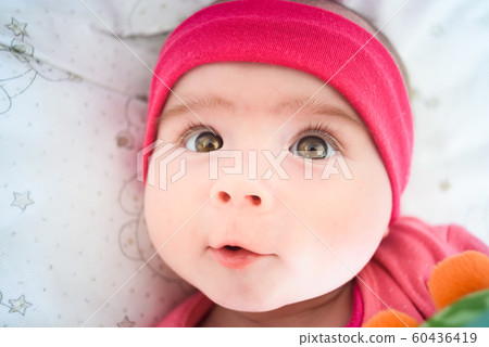 Beautiful portrait of 5 week old baby girl lying in a crib looking up towards camera. Baby care concept Beautiful portrait of 5 week old baby girl lying in a crib looking up towards camera. Baby care concept 60436419