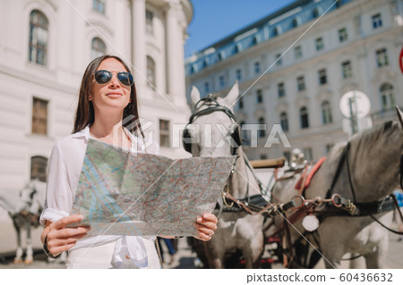Young woman with a city map in city. Travel tourist girl with map in Vienna outdoors during holidays in Europe. Young woman with a city map in city. Travel tourist girl with map in Vienna outdoors during holidays in Europe. 60436632