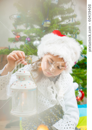Nice girl in a Christmas hat with a candlestick in her hands, Fur-tree 60439408