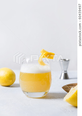 Whiskey sour cocktail - bourbon with lemon juice, sugar syrup and egg white in glass. Vertical orientation. 60439497