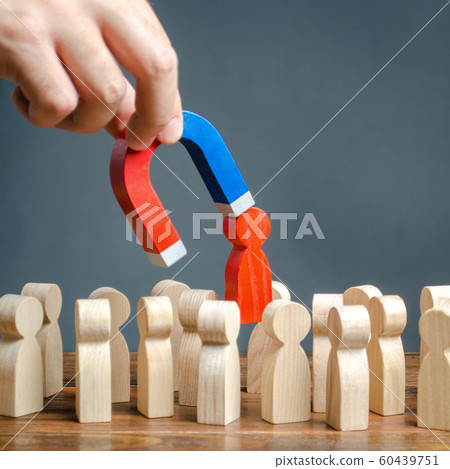 The hand with a magnet pulls out a red figure of a man from the crowd. Increase team efficiency, productivity. leader manages the business and forms a team. toxic, incompetent worker. 60439751