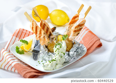 Delicious jacket potato with sour cream and grilled salmon skewers Delicious jacket potato with sour cream and grilled salmon skewers 60440529