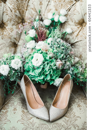 Pair of elegant and stylish bridal shoes and a bouquet of roses and other flowers Pair of elegant and stylish bridal shoes and a bouquet of roses and other flowers 60441833