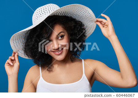 Playful woman wearing summer straw hat with wide brims Playful woman wearing summer straw hat with wide brims 60446067