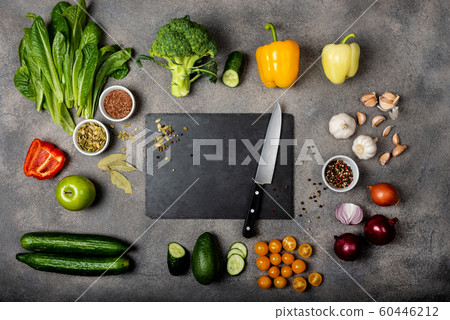Ingredients for preparing a healthy food. Different vegetables and spices and a black board with a knife on a gray background. Diet concept. Top view with space for text. 60446212