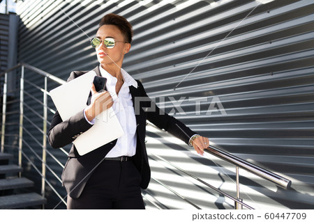 Caucasian woman in office clothes do freelance with laptop and waits colleague near the office Caucasian woman in office clothes do freelance with laptop and waits colleague near the office 60447709