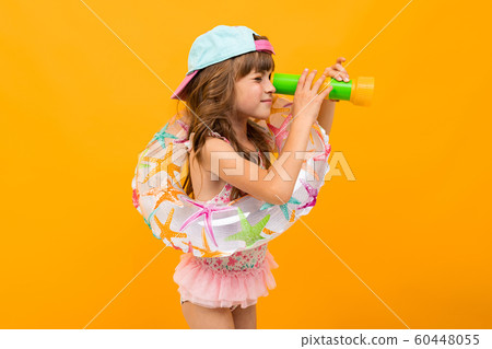 little girl with a baseball cap in a swimsuit with a swimming circle on a yellow background little girl with a baseball cap in a swimsuit with a swimming circle on a yellow background 60448055
