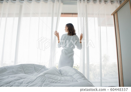 Woman open white curtains at the window, the 60448337