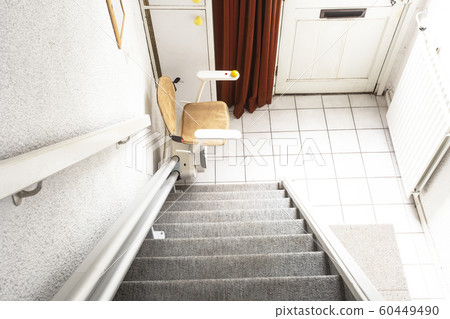 Automatic stair lift on staircase taking elderly people and disabled persons up and down in a house Automatic stair lift on staircase taking elderly people and disabled persons up and down in a house 60449490