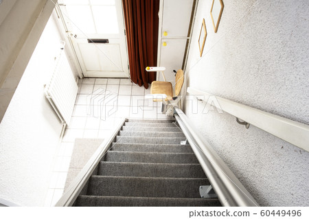 Automatic stair lift on staircase taking elderly people and disabled persons up and down in a house Automatic stair lift on staircase taking elderly people and disabled persons up and down in a house 60449496