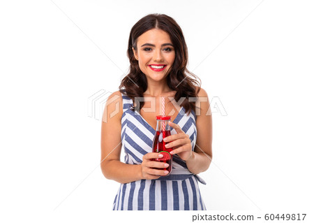 attractive brunette girl in a striped dress with a neckline with a glass of cocktail on a white attractive brunette girl in a striped dress with a neckline with a glass of cocktail on a white 60449817