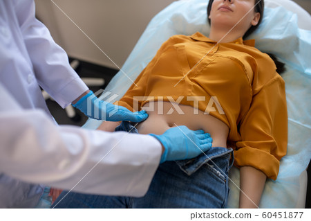 Blond doctor wearing sterile gloves working with female patient Blond doctor wearing sterile gloves working with female patient 60451877