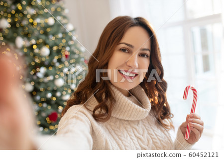 Dark-haired woman near christmas tree making selfie 60452121