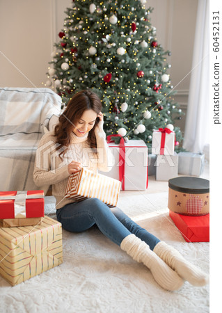 Dark-haired young woman opening her christmas gifts 60452131