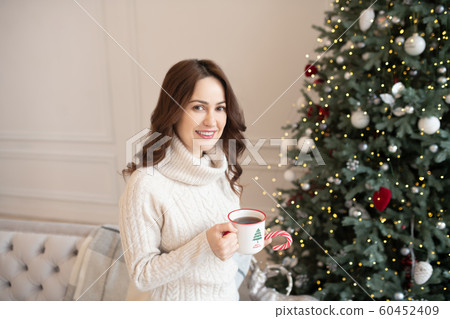 Dark-haired young pretty woman in thick sweater feeling happy Dark-haired young pretty woman in thick sweater feeling happy 60452409
