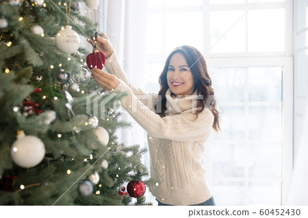Young pretty smiling woman decorating christmas tree Young pretty smiling woman decorating christmas tree 60452430