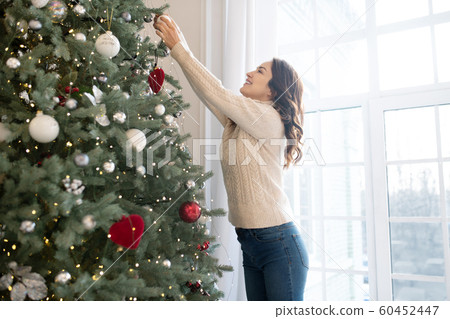 Pretty slim woman in jeans decorating christmas tree 60452447
