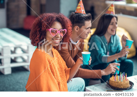 Birthday girl wearing pink glasses smiling broadly while feeling happy 60453130