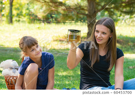 Girl and girl have fun at a teapot at a picnic Girl and girl have fun at a teapot at a picnic 60453700