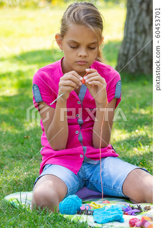 Girl knits on a knitting needles on a picnic in Girl knits on a knitting needles on a picnic in 60453701