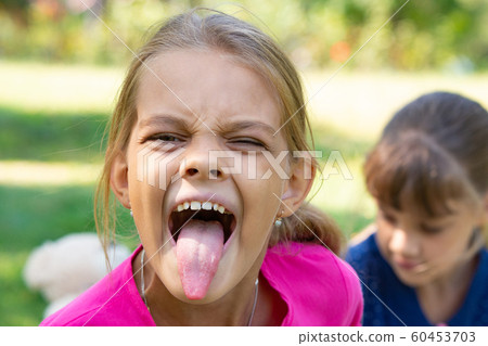 The girl turned and funny shows a long tongue The girl turned and funny shows a long tongue 60453703