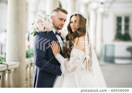 Beautiful young wedding couple posing with bouquet of flowers in hands 60456099