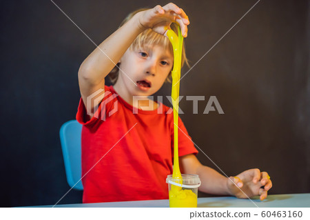Boy playing hand made toy called slime. Child play with slime. Kid squeeze and stretching slime Boy playing hand made toy called slime. Child play with slime. Kid squeeze and stretching slime 60463160