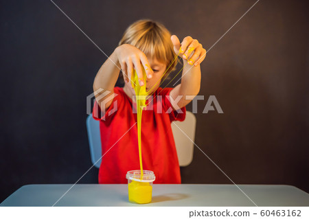Boy playing hand made toy called slime. Child play with slime. Kid squeeze and stretching slime Boy playing hand made toy called slime. Child play with slime. Kid squeeze and stretching slime 60463162