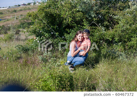 Beautiful mom with her son on a picnic rest in nature Beautiful mom with her son on a picnic rest in nature 60467372